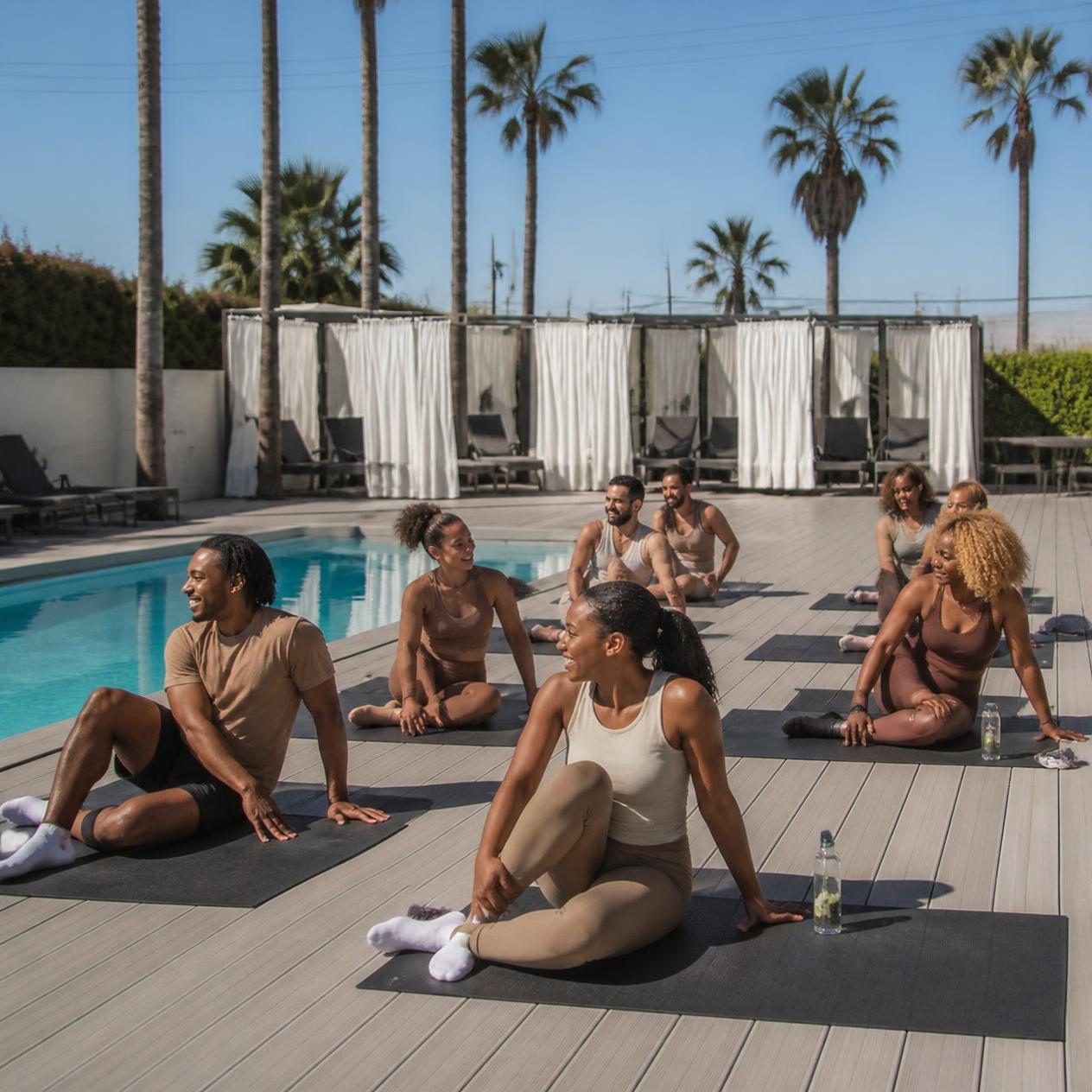 Friends stretching on their mats by the pool after a Pilates class